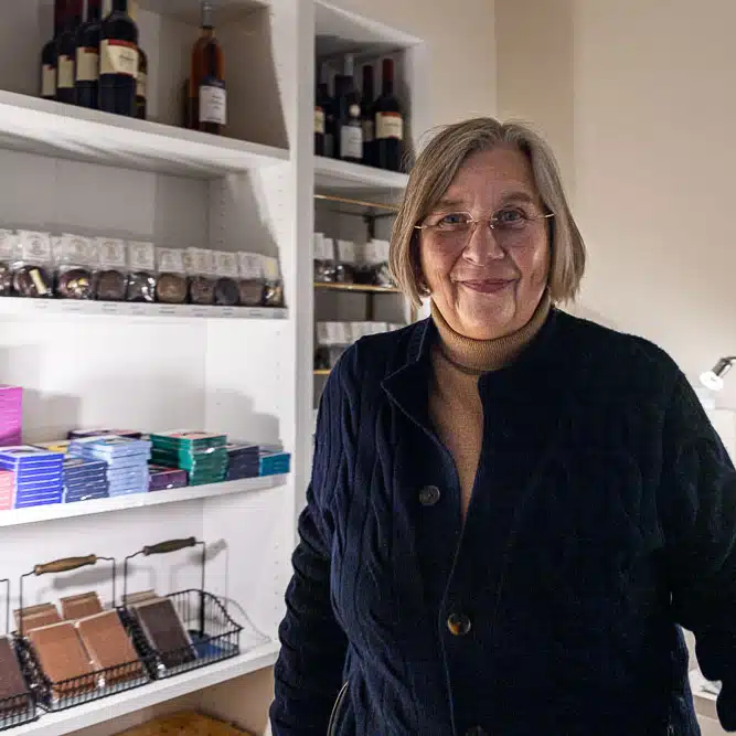 Angela Evers vor einem Regal mit Schokolade und Wein im Geschäft.